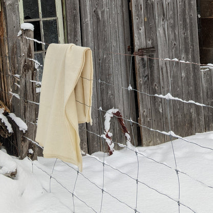 Old wooden barn with a white blanket hanging on a hook in a snowy landscape